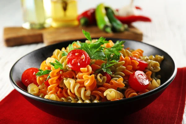 Delizioso piatto di maccheroni in ciotola nera su tovagliolo di cotone rosso, da vicino — Foto Stock