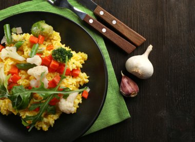 Hizmet ahşap masa üzerinde sebze risotto ile siyah plaka