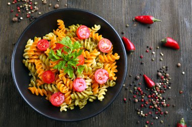 Üzerinde siyah kase lezzetli makarna yemek biber ahşap masa ile dekore edilmiştir.