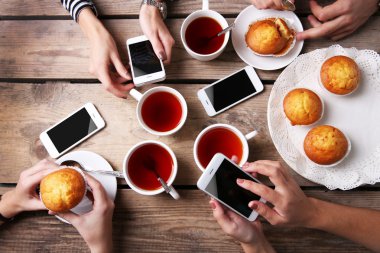 Bardak çay, ahşap masa arka planda tutarak akıllı telefonlar ile dört el