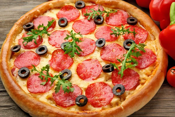 Tasty pizza with salami and red vegetables on wooden background, close up — Stock Photo, Image