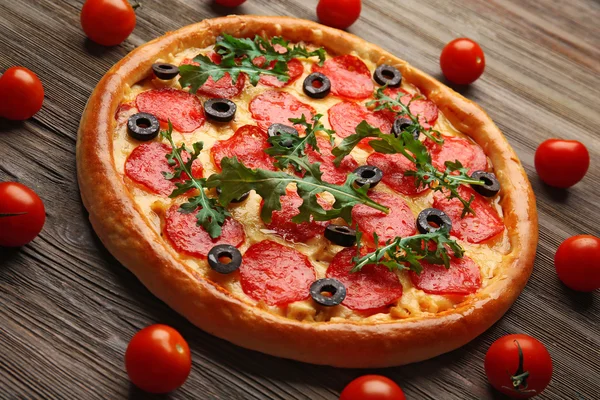 Gustosa pizza con salame decorato con pomodori su sfondo di legno — Foto Stock