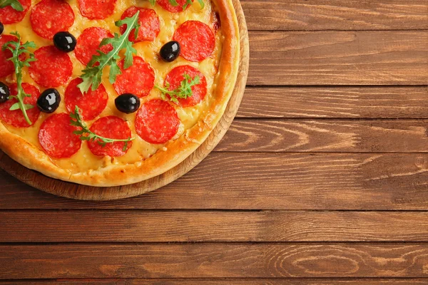 Ízletes pizza, szalámi és olajbogyó, fából készült háttér — Stock Fotó