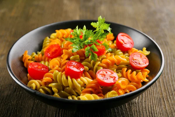 Delicioso plato de macarrones en tazón negro sobre fondo de madera — Foto de Stock