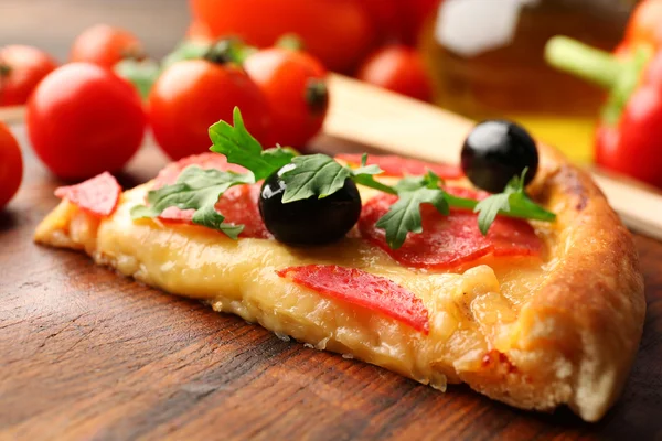 Delicioso pedazo sabroso de pizza con verduras sobre fondo de madera, de cerca —  Fotos de Stock