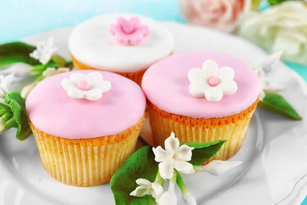 Gustosi cupcake su piatto, su sfondo di legno a colori — Foto Stock