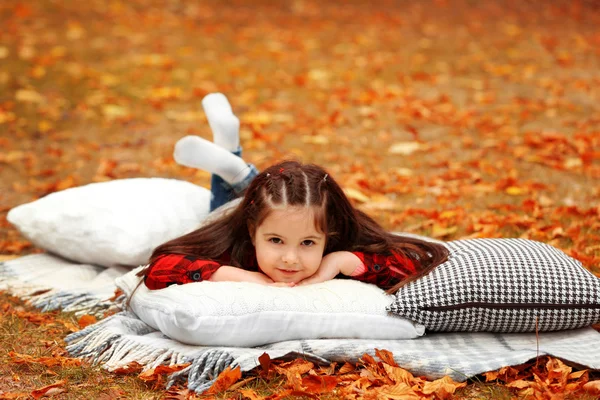 Gelukkig jong meisje liggend op plaid in herfst park — Stockfoto