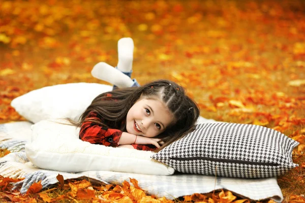 Gelukkig jong meisje liggend op plaid in herfst park — Stockfoto