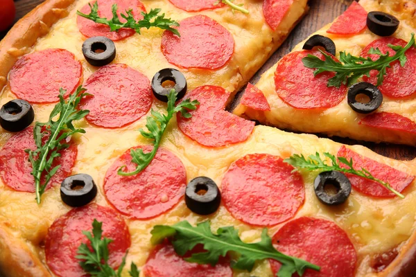 Pizza gostosa quente com salame e azeitonas em fundo de madeira, close-up — Fotografia de Stock