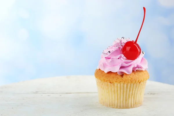 Tasty cupcake on color wooden table, on bright background — Stock Photo, Image