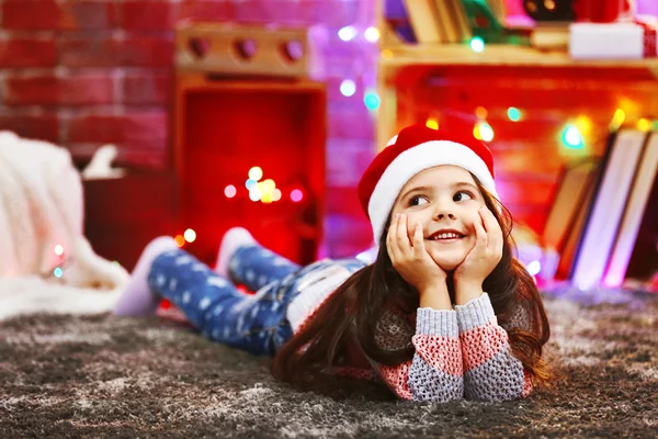 Linda niña en el sombrero rojo que pone en la habitación decorada de Navidad —  Fotos de Stock
