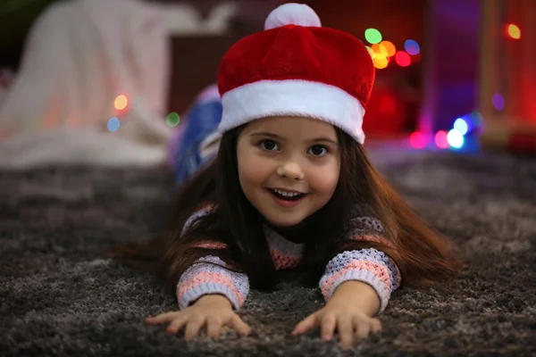 Linda niña en el sombrero rojo que pone en la habitación decorada de Navidad —  Fotos de Stock