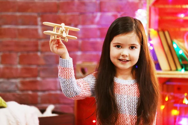 크리스마스 장식 방에 나무 비행기를 노는 예쁜 소녀 — 스톡 사진