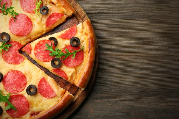 Pizza gostosa quente com salame e azeitonas em fundo de madeira — Fotografia de Stock