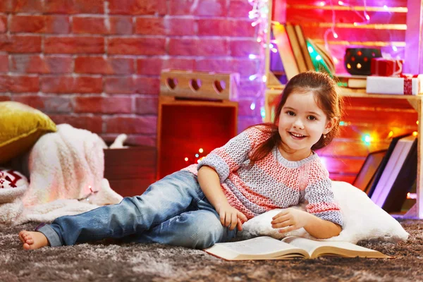 Linda niña con libro en la habitación decorada de Navidad —  Fotos de Stock