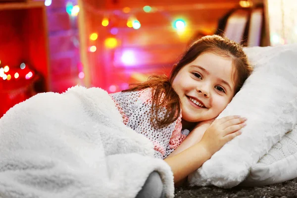 Sevimli küçük kız Noel dekore edilmiş oda yumuşak ekose altında yastık üzerinde döşeme — Stok fotoğraf