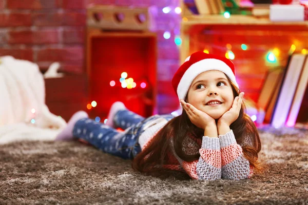 Menina bonita em chapéu vermelho que coloca no quarto decorado de Natal — Fotografia de Stock