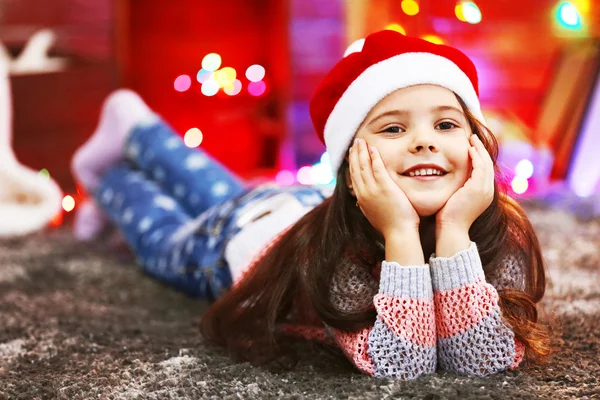 Linda niña en el sombrero rojo que pone en la habitación decorada de Navidad —  Fotos de Stock