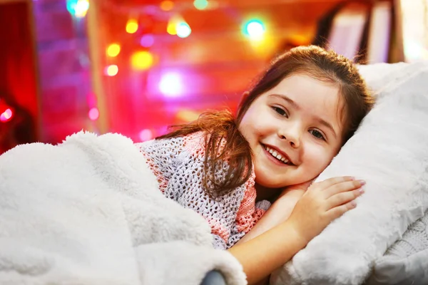 Красивая маленькая девочка лежала на подушке под мягкой клеткой в украшенной рождественским убранством комнате — стоковое фото