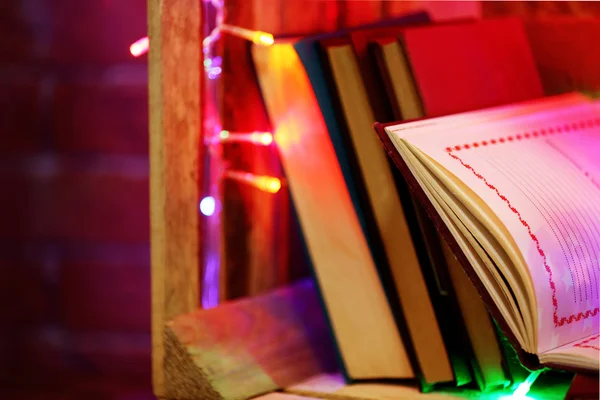 Książki na półce drewniane ozdobione kolorowymi światłami, z bliska — Zdjęcie stockowe