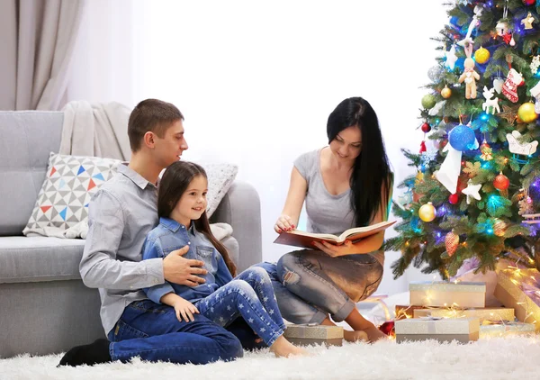 सुशोभित ख्रिसमस खोलीत आनंदी कुटुंब पुस्तक वाचा — स्टॉक फोटो, इमेज