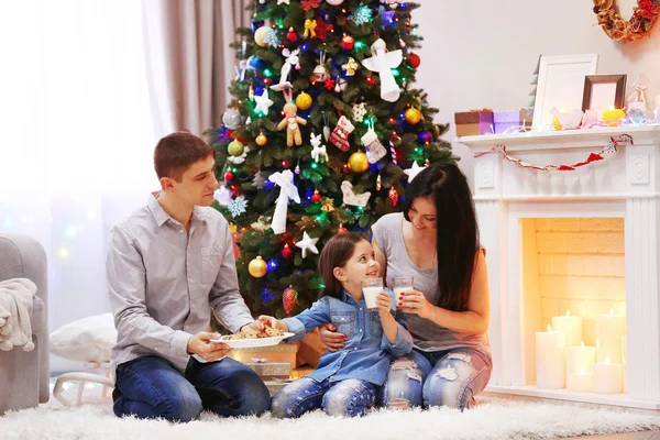 Lycklig familj med mjölk och söta kakor i den inredda jul rum — Stockfoto