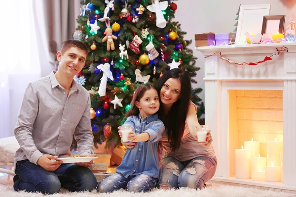 Família feliz com leite e biscoitos doces na sala de Natal decorada — Fotografia de Stock