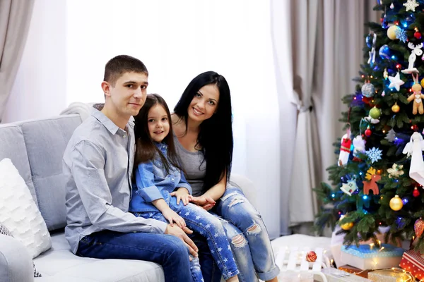 Famiglia felice seduta sul divano nella stanza decorata di Natale — Foto Stock