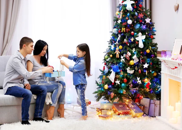Familia cariñosa: madre, padre e hija en la habitación de Navidad decorada — Foto de Stock