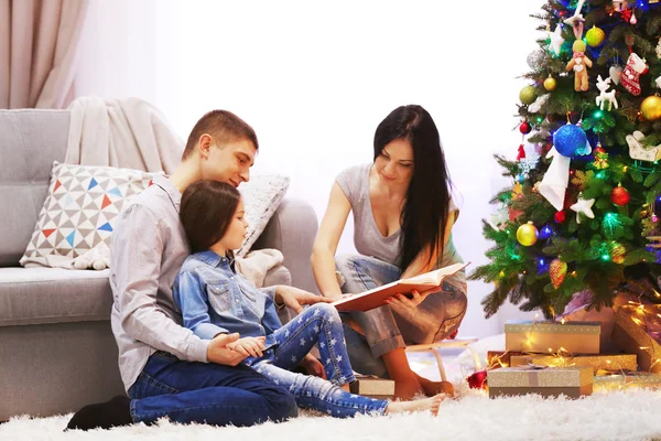 Ευτυχισμένη οικογένεια διαβάσει βιβλίο στο διακοσμημένο δωμάτιο Χριστούγεννα — Φωτογραφία Αρχείου