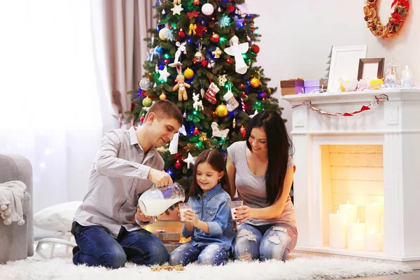 Feliz familia beber leche en la habitación de Navidad decorada —  Fotos de Stock