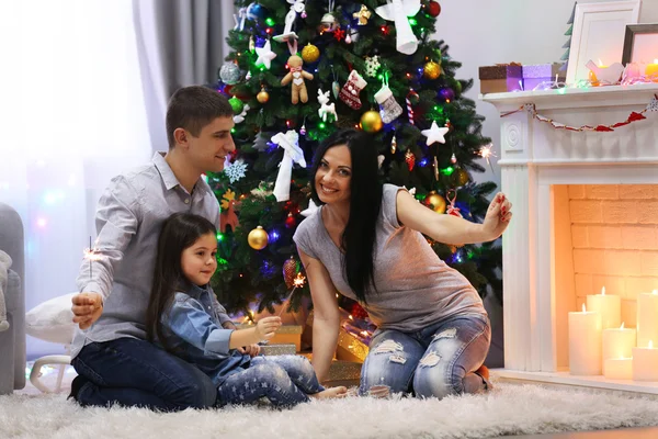 Joyeux famille avec des lumières du Bengale dans la salle de Noël décorée — Photo