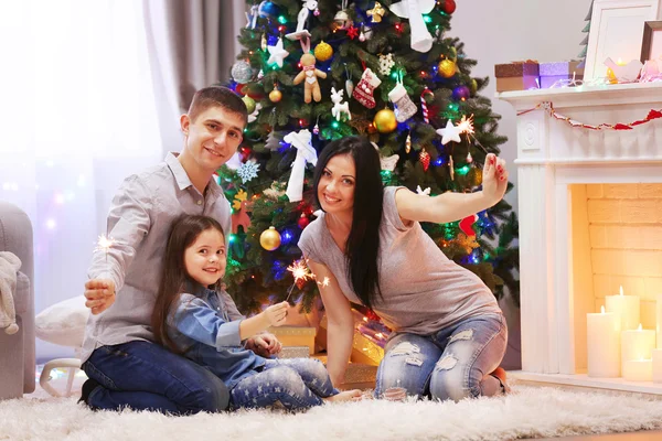 Joyeux famille avec des lumières du Bengale dans la salle de Noël décorée — Photo