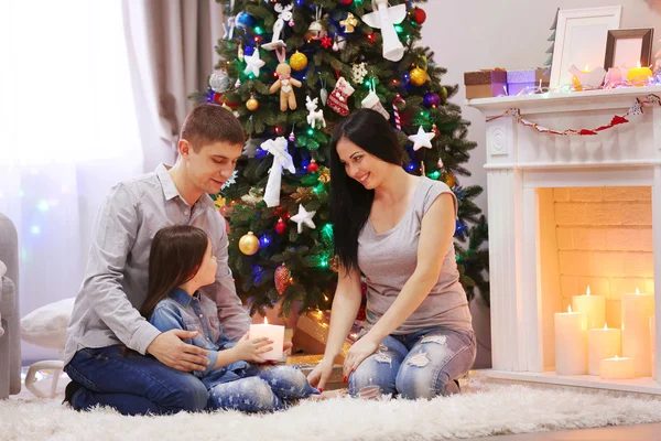 Joyeux famille tiennent ensemble bougie dans les mains dans la salle de Noël décorée — Photo