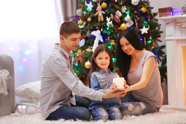 A família feliz em conjunto mantém a vela em mãos na sala de Natal decorada — Fotografia de Stock