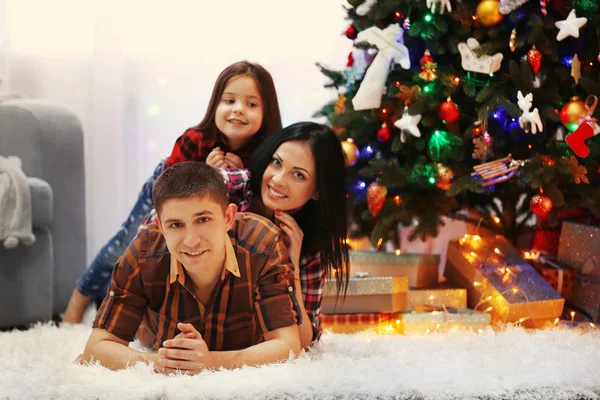Familia feliz en el suelo en la habitación de Navidad decorada —  Fotos de Stock