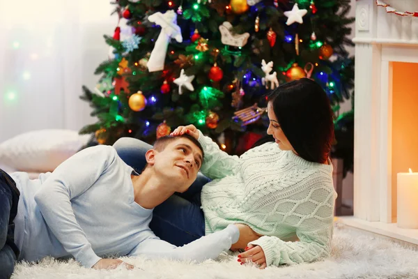 Feliz pareja abrazar en el suelo en la habitación de Navidad decorada — Foto de Stock