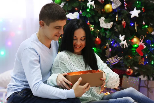 Szczęśliwa para na podłodze z darów w urządzonych pokojach Boże Narodzenie — Zdjęcie stockowe
