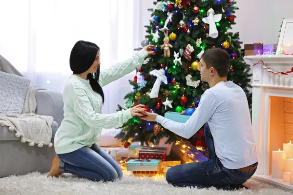 Joyeux couple sur le sol avec des cadeaux dans la salle de Noël décorée — Photo