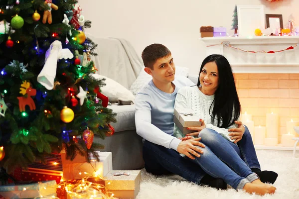 Lyckliga par på golvet med gåvor i den inredda jul rum — Stockfoto