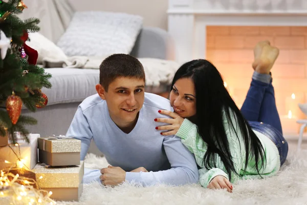 Casal feliz no chão com presentes na sala de Natal decorada — Fotografia de Stock