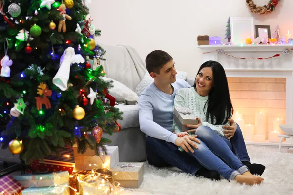 Glückliches Paar auf dem Fußboden mit Geschenken im geschmückten Weihnachtszimmer — Stockfoto