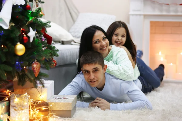 Famiglia felice sul pavimento con regali nella stanza decorata di Natale — Foto Stock