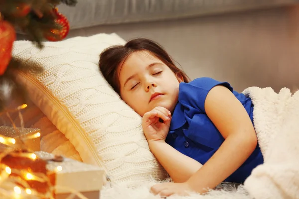 Linda niña durmiendo en un acogedor sofá en la habitación decorada con Navidad —  Fotos de Stock