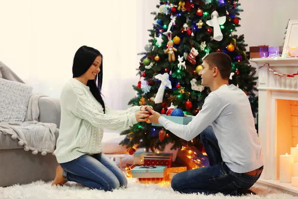 Joyeux couple sur le sol avec des cadeaux dans la salle de Noël décorée — Photo