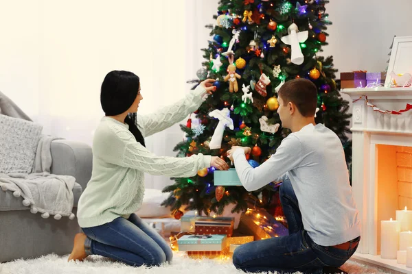 Casal feliz no chão com presentes na sala de Natal decorada — Fotografia de Stock