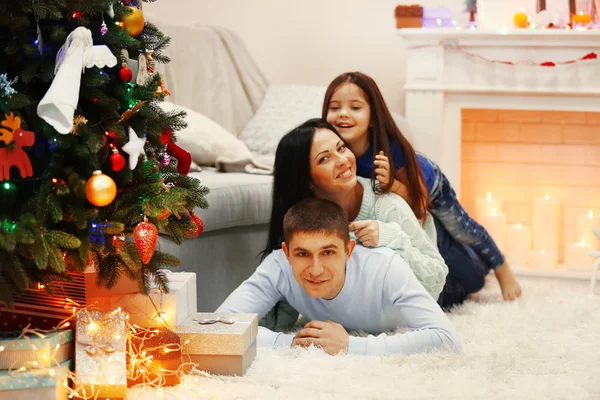 Familia feliz en el suelo con regalos en la habitación de Navidad decorada —  Fotos de Stock