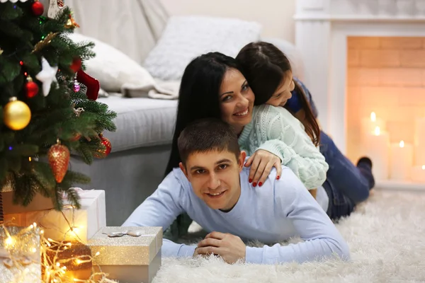 Famiglia felice sul pavimento con regali nella stanza decorata di Natale — Foto Stock