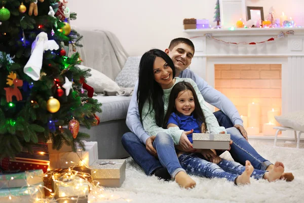 Familia feliz en el suelo con regalos en la habitación de Navidad decorada —  Fotos de Stock