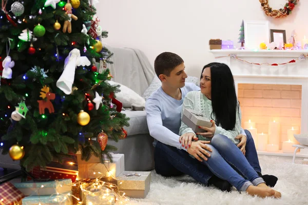 Coppia felice sul pavimento con regali nella stanza decorata di Natale — Foto Stock